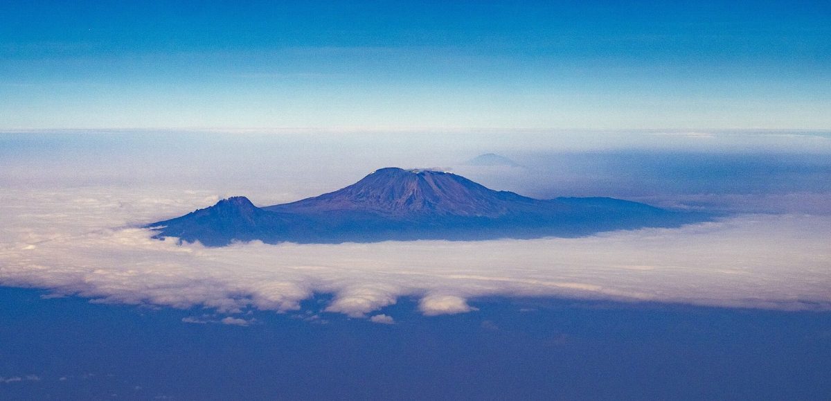 Kilimanjaro's summit seen from the air, rising above a thick layer of cloud.