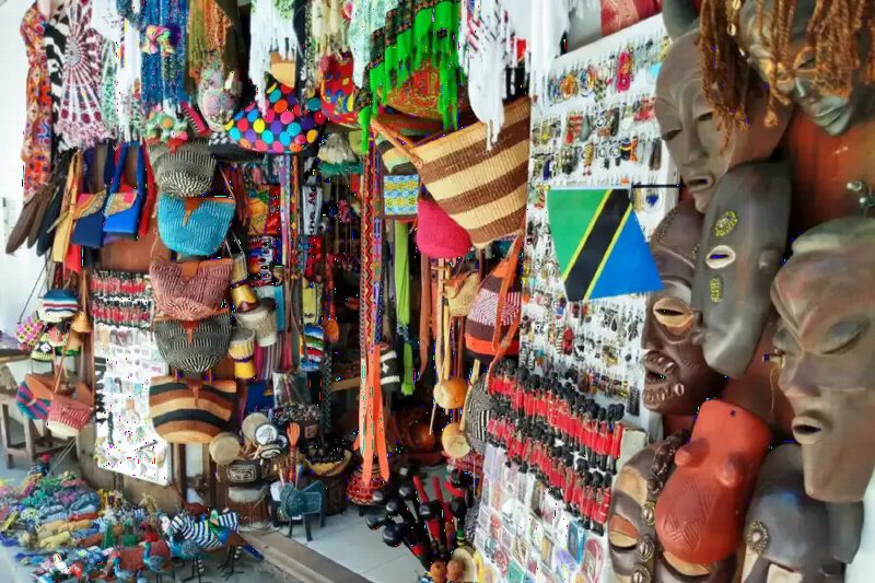 Rows of carved masks, beaded jewellery and colourful crafts in a market stall.